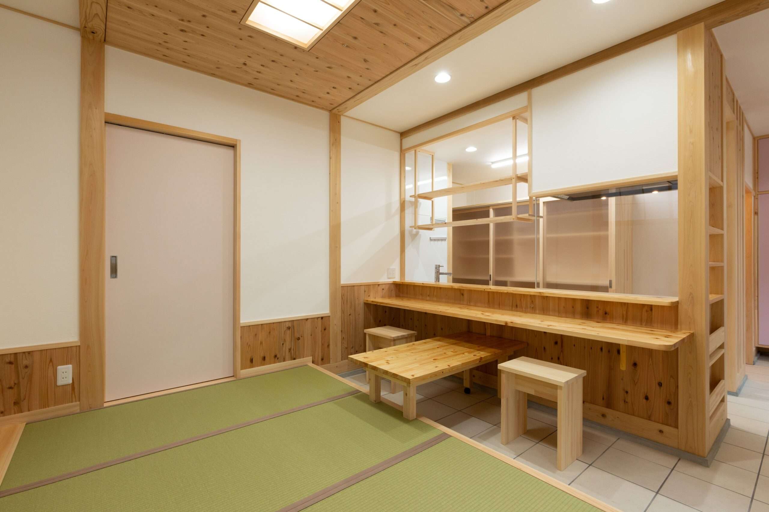 無垢材の天井と長い木製カウンター、一段上がった畳の小上がりのある部屋