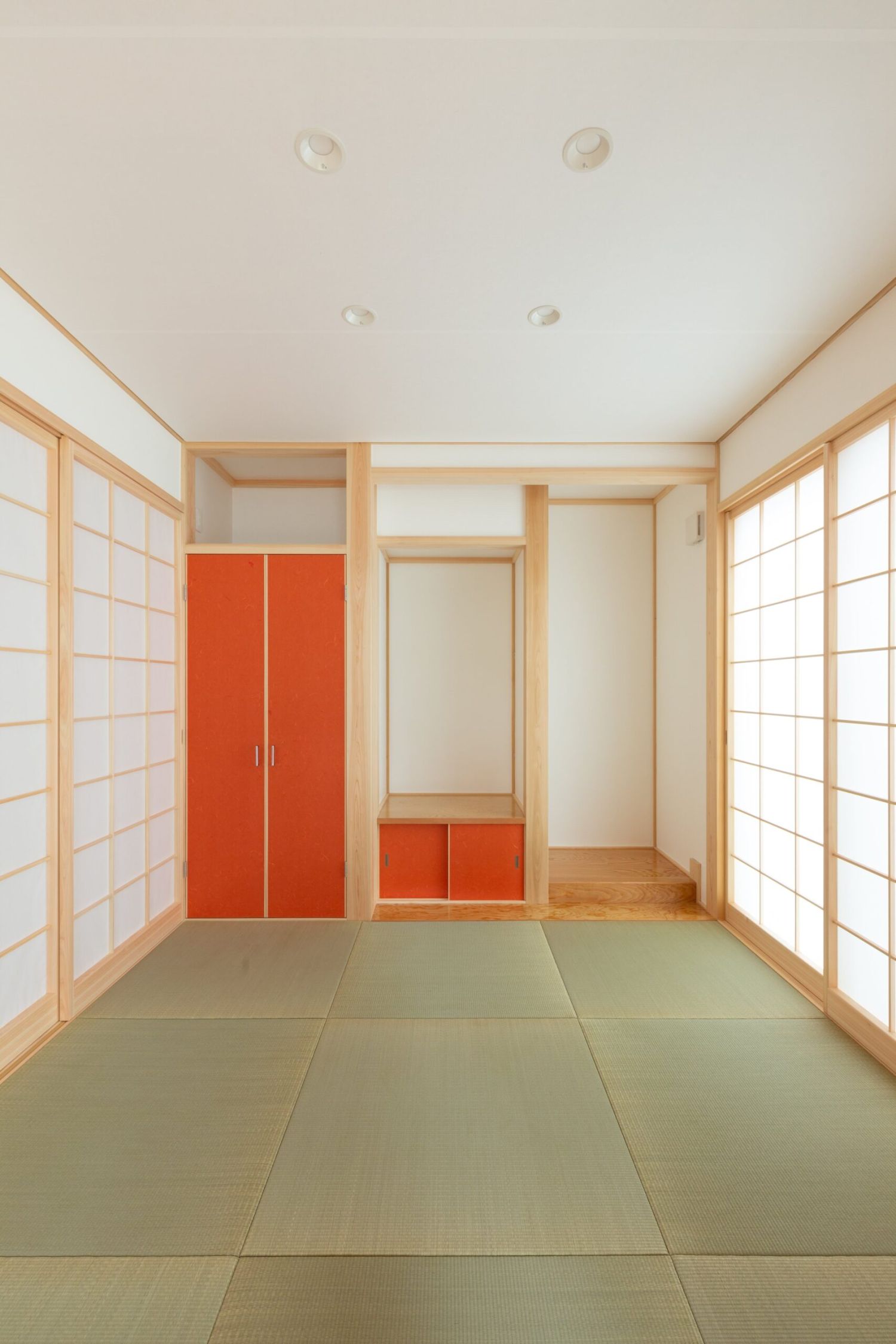 両側に障子を配した畳の和室。朱色の扉の造作収納がある