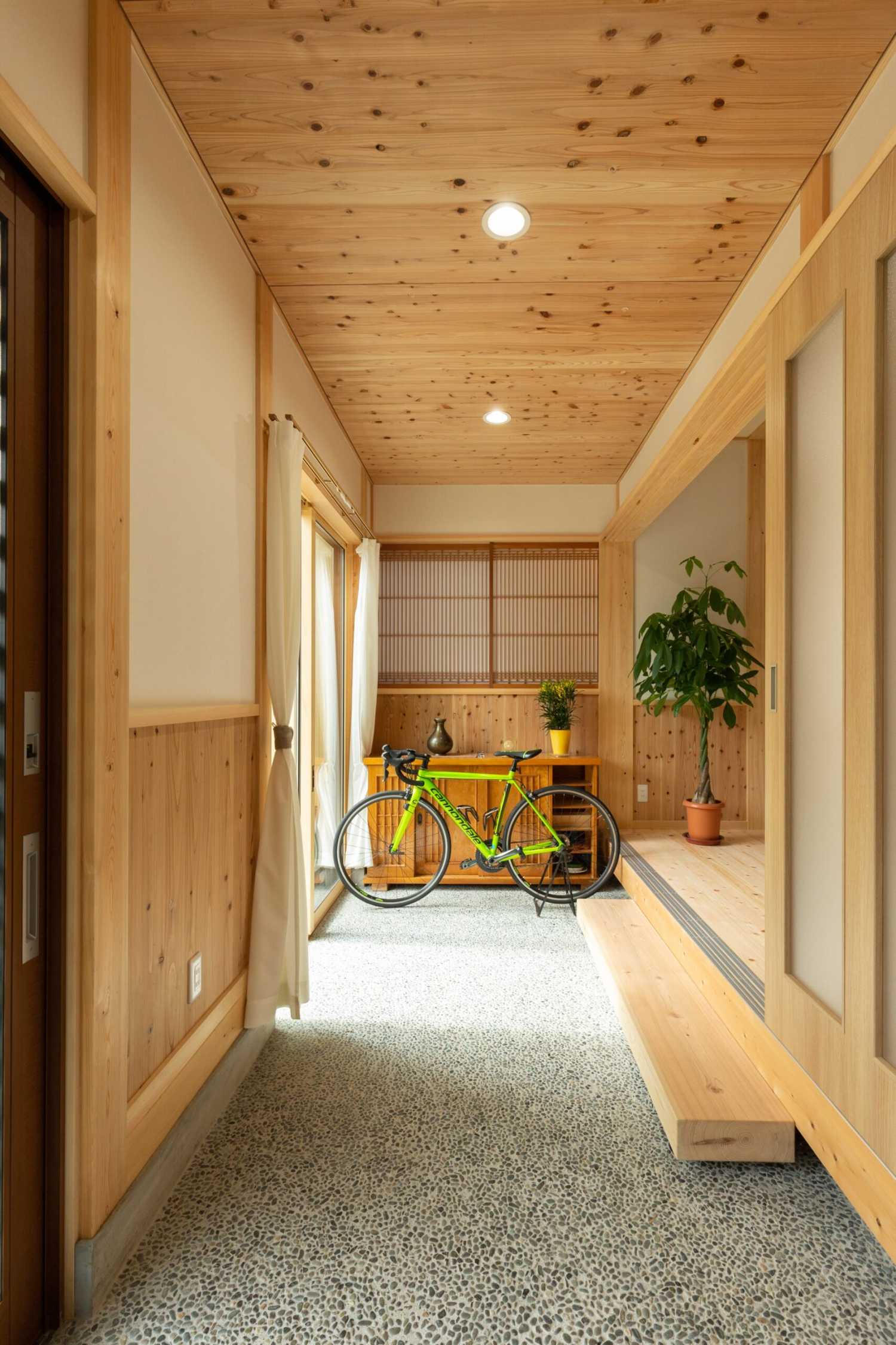 木目の天井と壁に囲まれた玄関土間に停めた自転車