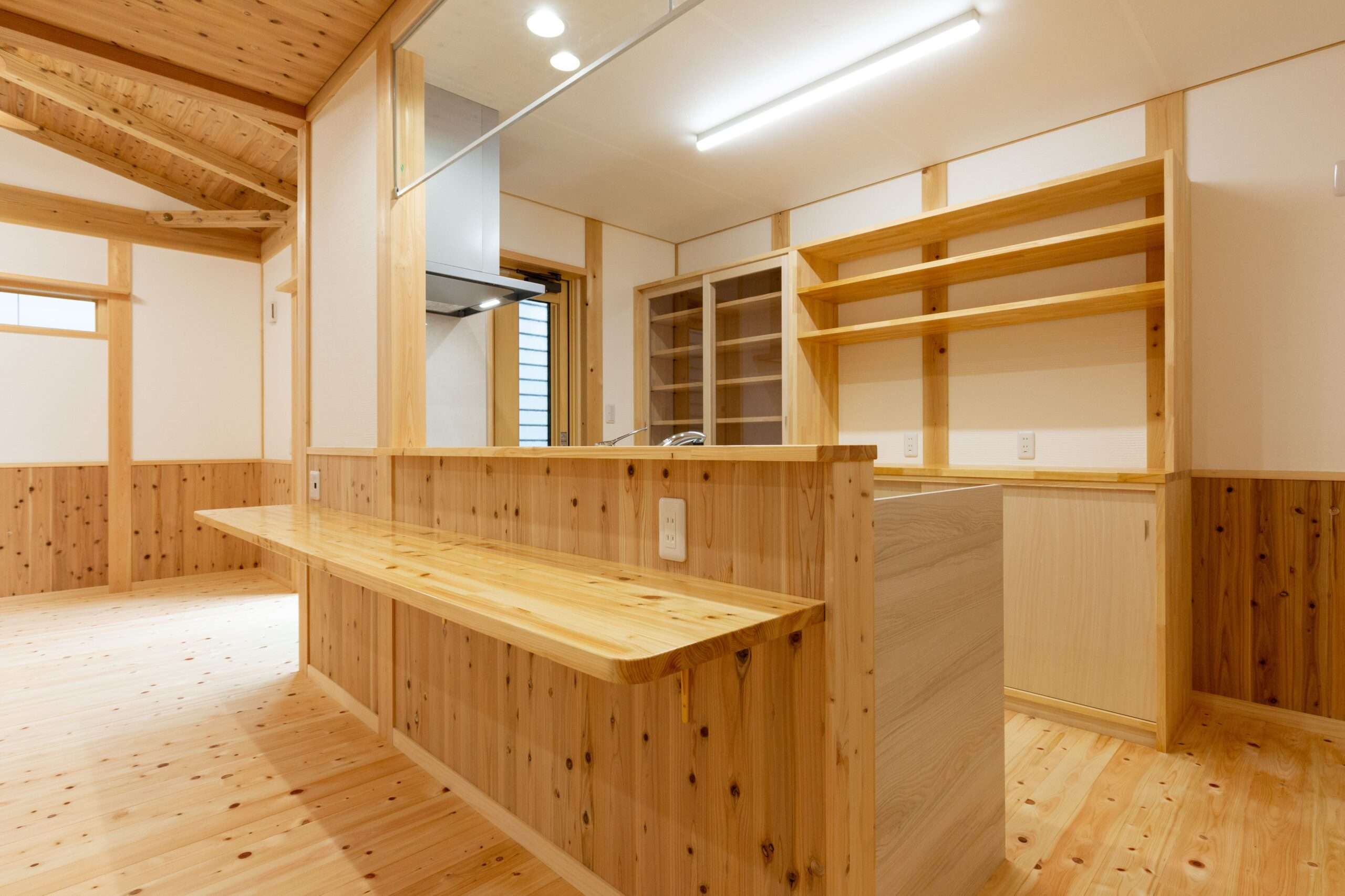無垢材の造作カウンターと背面収納を備えた対面式キッチン。