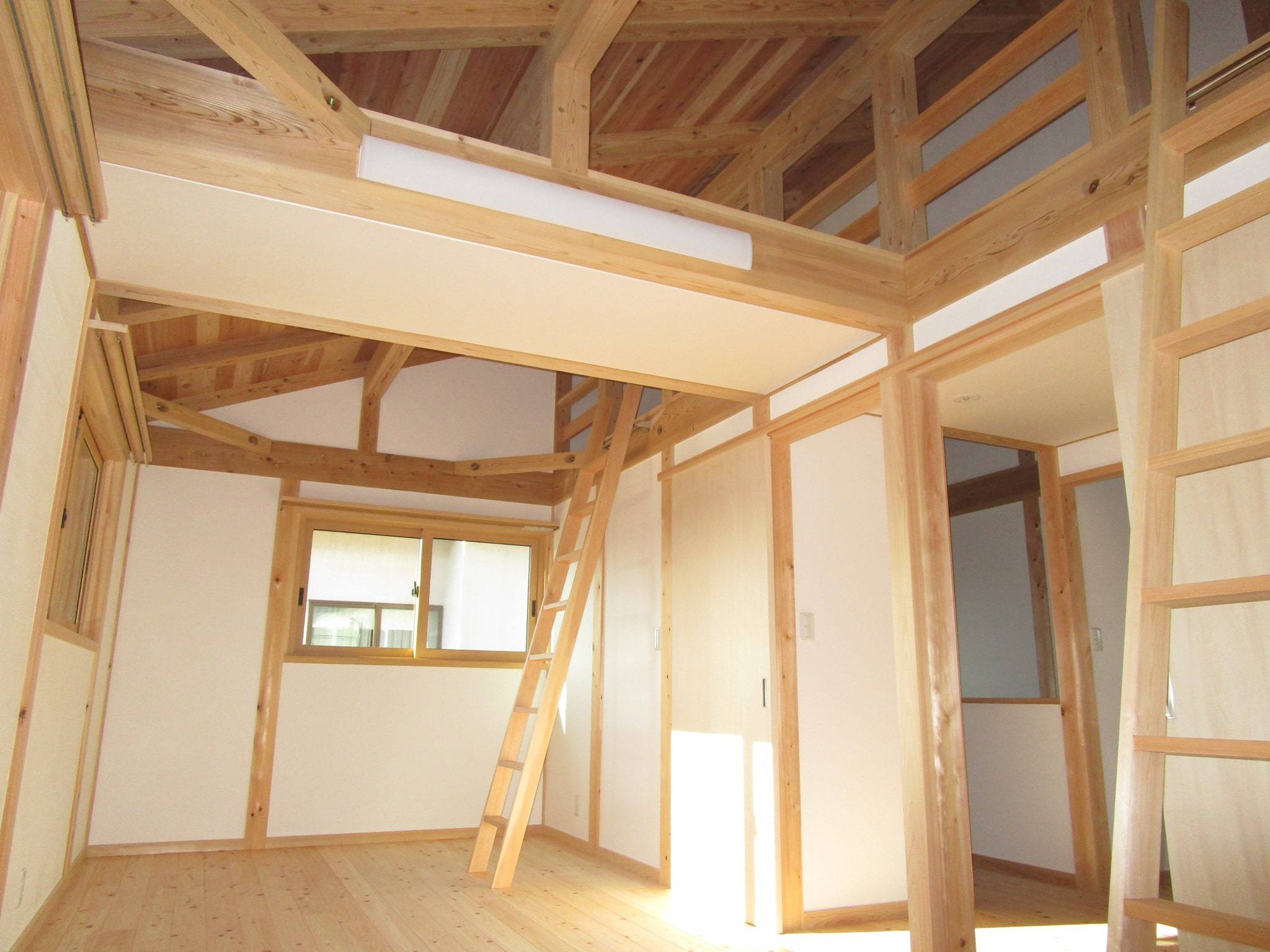 表出した木組みの小屋組みとロフトハシゴが印象的な部屋