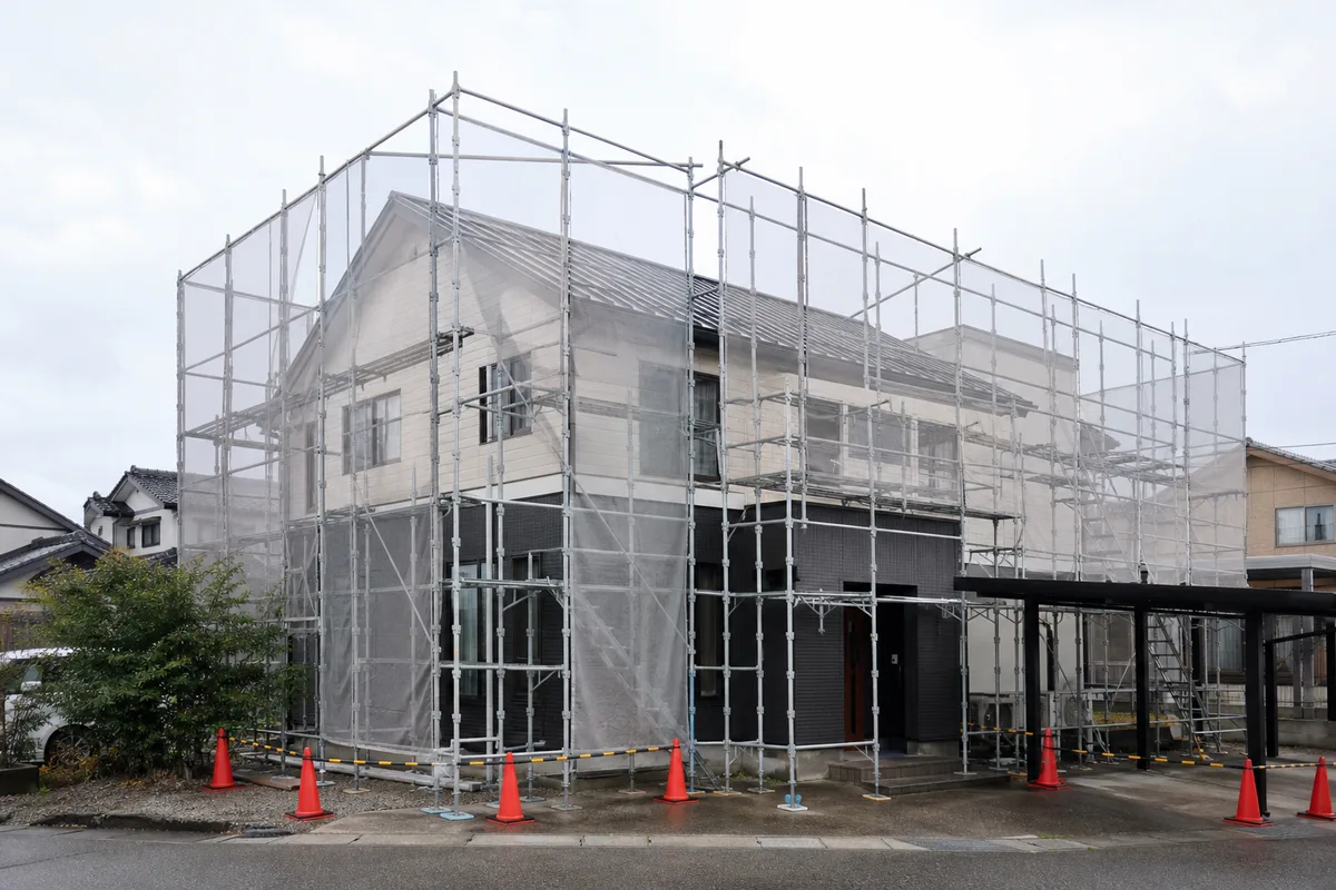 外壁と屋根のリフォームに備えて足場と養生を設置した戸建て住宅